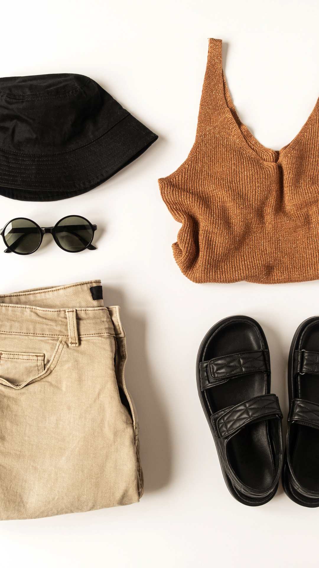 Flatlay-of-casual-outfit-for-women-featuring-brown-top-pant-black-sandals-a-round-cap-and-sunglasses-for-everyday-style-inspiration