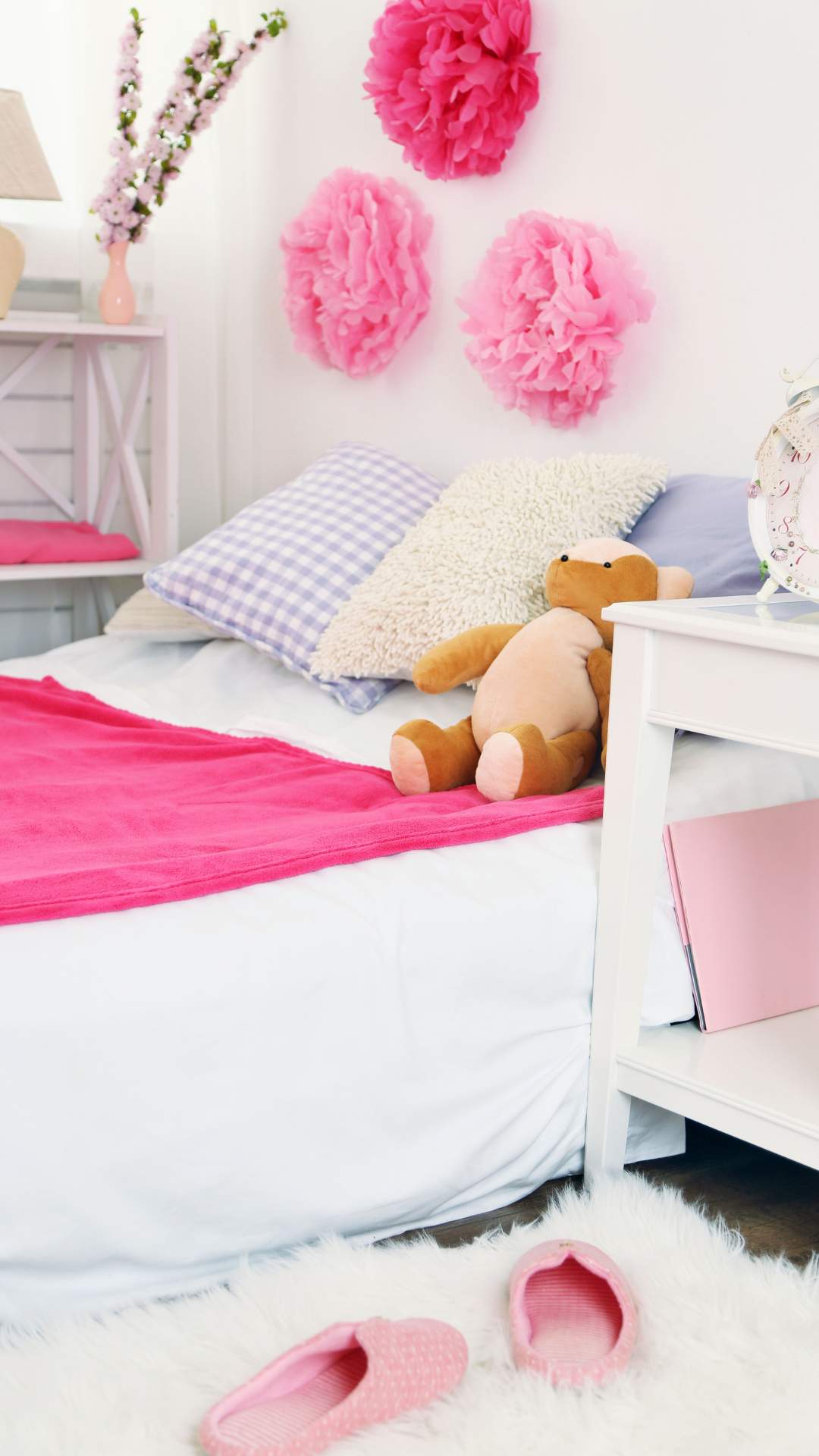 A-girly-bedroom-with-pink-bedding-decorative-paper-pompoms-on-the-wall-and-a-teddy-bear-on-the-bed