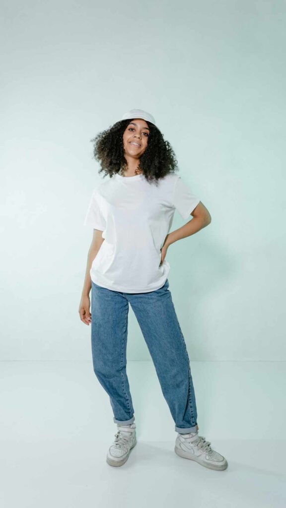 A-woman-wearing-blue-high-waisted-jeans-white-button-down-shirt-white-sneakers