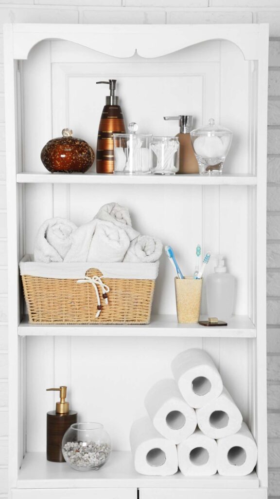 Bathroom-Makeover-Ideas-featuring-A-built-in-shelving-unit-displaying-bathroom-essentials-the-top-shelf-has-soap-dispensers-and-clear-jar-the-middle-shelf-holds-a-woven-basket-with-towels-and-a-toothbrush-and-the-bottom-shelf-features-a-stack-of-rolled-toilet-paper-and-another-soap-dispenser