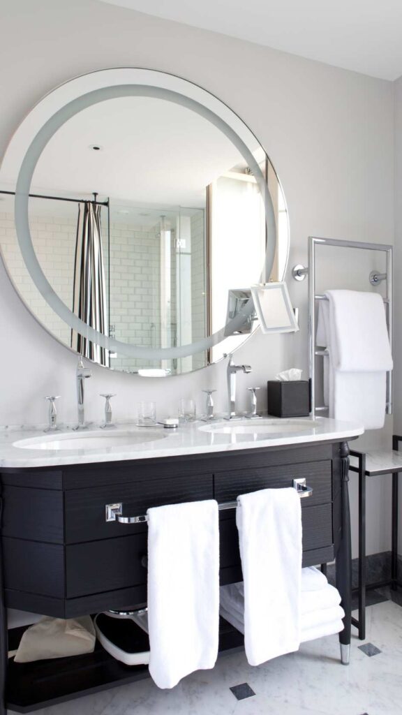 A-stylish-bathroom-featuring-modern-matte-black-faucets-a-sleek-mirror-with-a-metallic-frame-updated-cabinet-handles-with-towels on-the-handles-for-a-bathroom-makeover-ideas