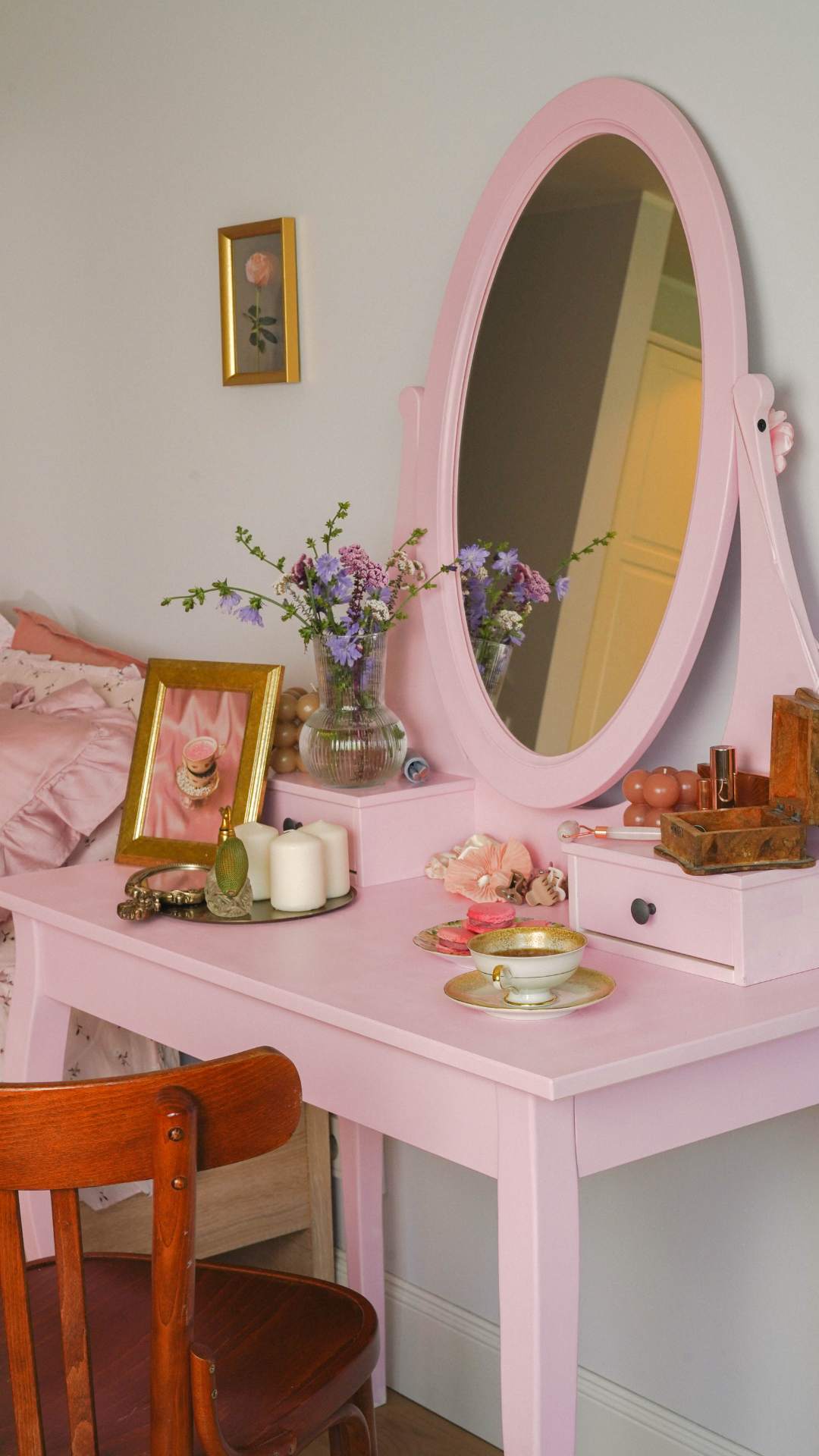Pink-vanity-table-with-an-oval-mirror-and-makeup-accessories-in-a-classic-girly-bedroom-setting