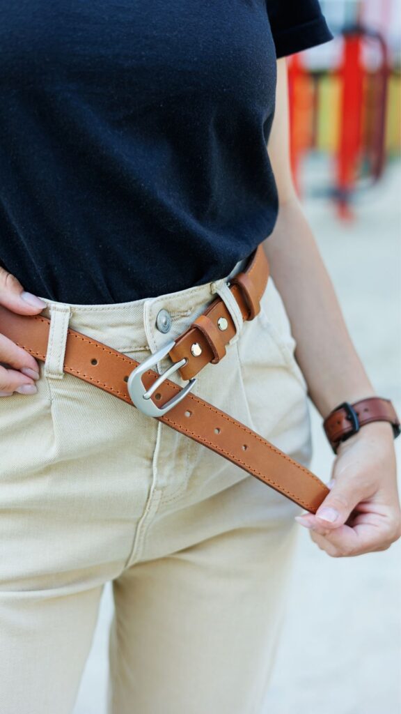 A-woman-wearing-black-top-and-cream-colored-pants-with-brown-belt