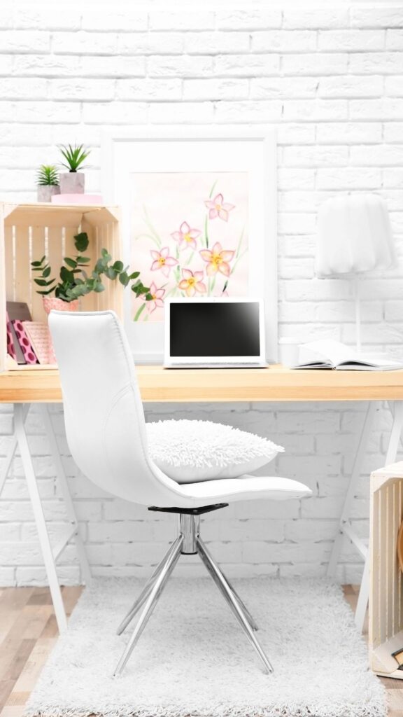 Comfortable-office-table-showing-lumbar-pillow-on-top-of-a-white-office-table-a-laptop-on-top-of-the-desk-and-a-mini-rug-spread-under-the-chair-as-feminine-office-ideas