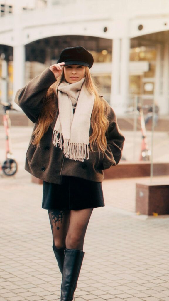 A-woman-wearing-a-layered-fall-outfits-comprising-of-boots-cap-sweater-and-skirt