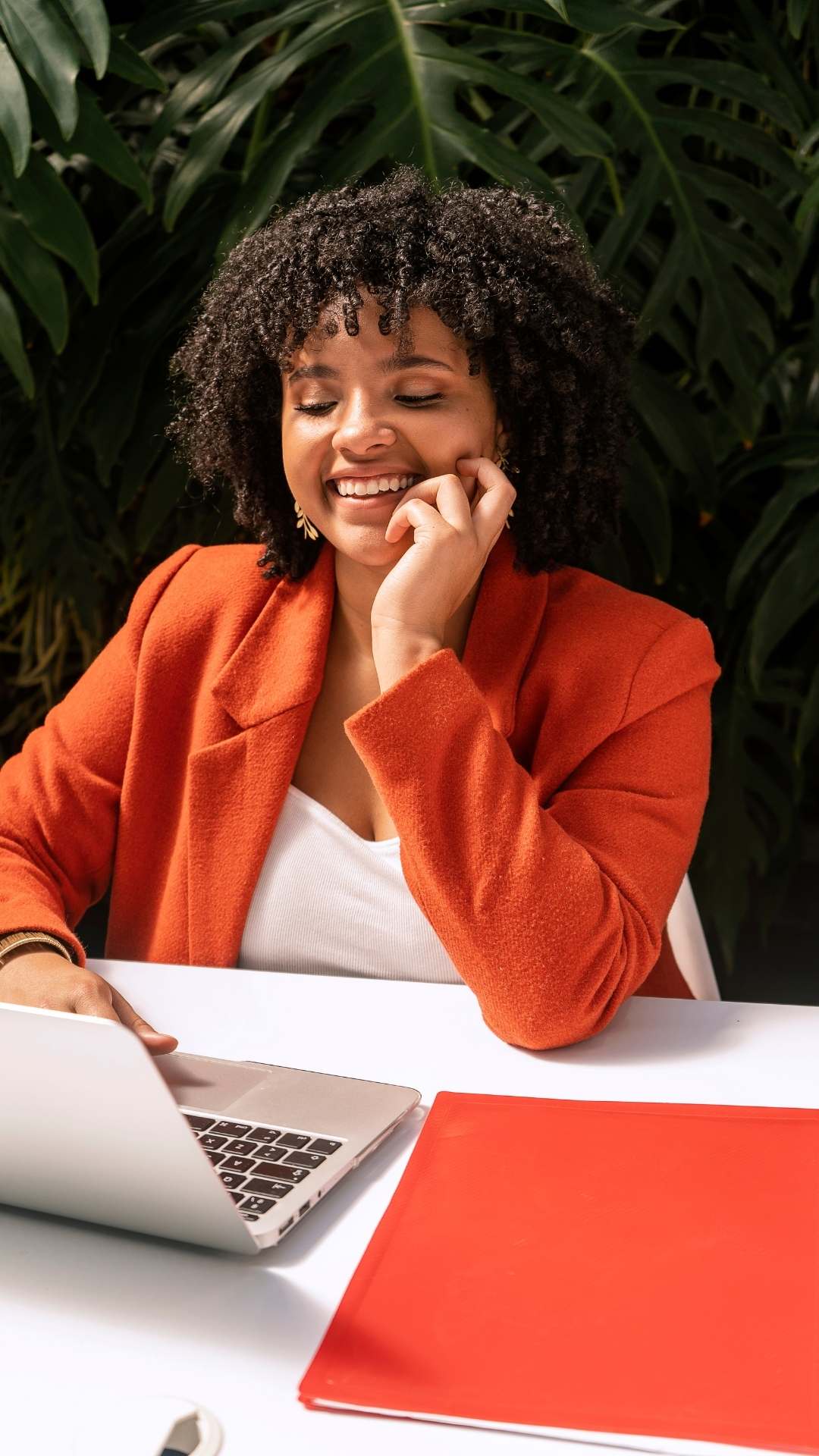 Woman-sitting-in-the-office-wearing-a-Valentine’s-Day-work-outfit-with-a-red-blazer-and-white singlet-stylish-and-professional.