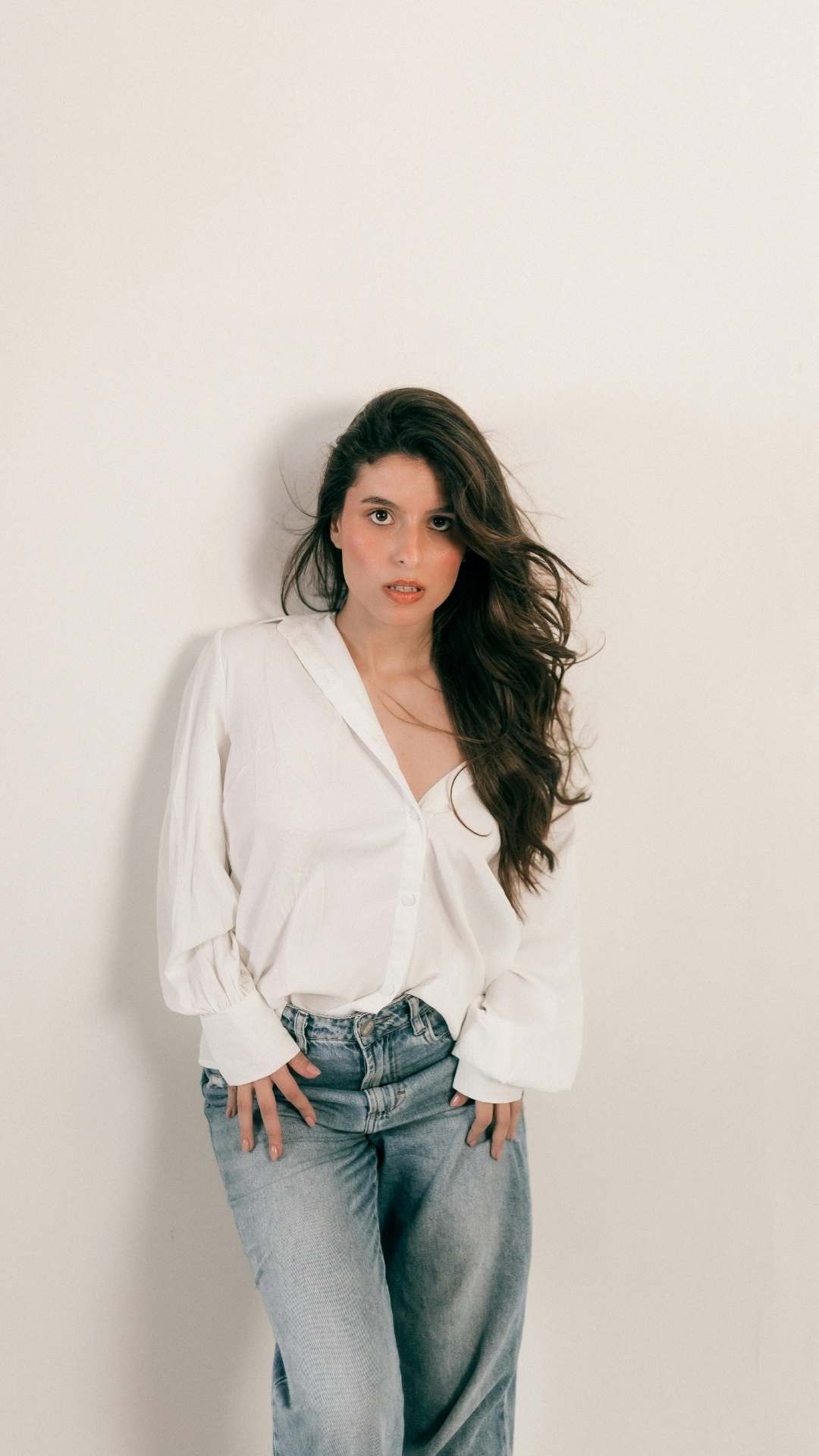 Cute-spring-outfit-with-jeans-featuring-a-woman-wearing-blue-jean-pants-and-a-stylish-white-shirt-worn-off-one-shoulder-for-a-relaxed-seasonal-look.