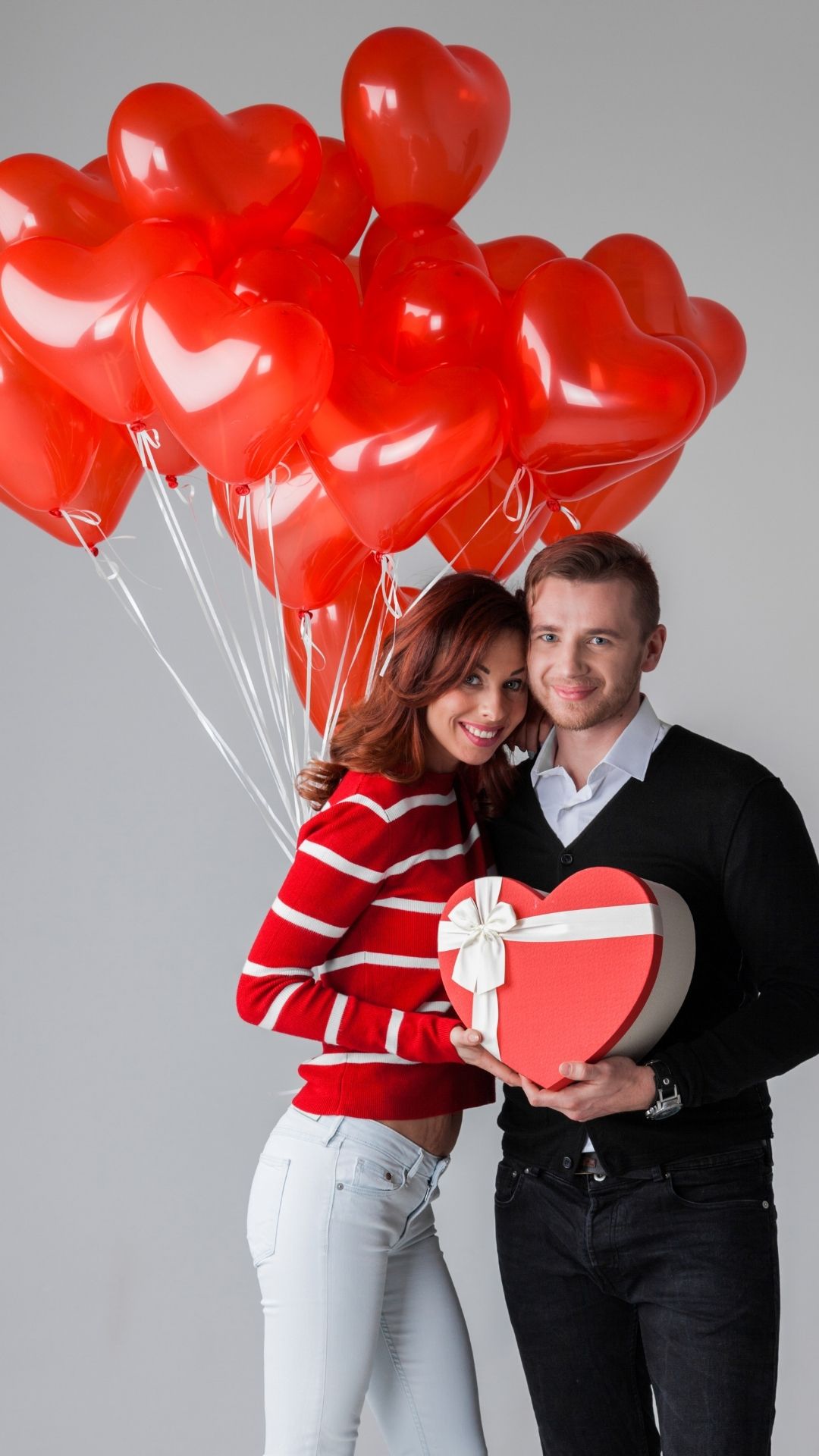 Featured-Image-of-couples-valentines-day-photshoot-ideas-showing-a-woman-wearing-red-white-top-and-white-trouser-and-a-man-weaeing-black-carrying-a-red-heart-box-and-the-woman-holding-a-red-balloon-