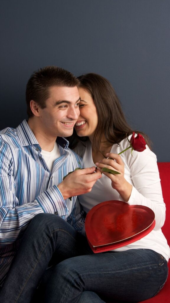 Natural-poses-for-couples-valentines-day-photoshoot-ideas-showing-lovers-wearing-different-colored-clothes-while-holding-a-rose-flower-and-a-heart-shaped-box-for-a-photoshoot