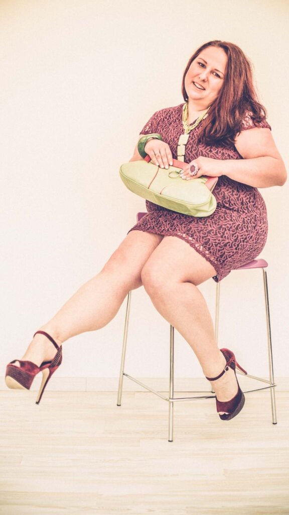 Plus-size-Valentine’s-Day-outfits-showcasing-romantic-dresses-and-elegant-styling-wearing red-heels-and-red-dress-sitting-down-to-celebrate-love-and-confidence.