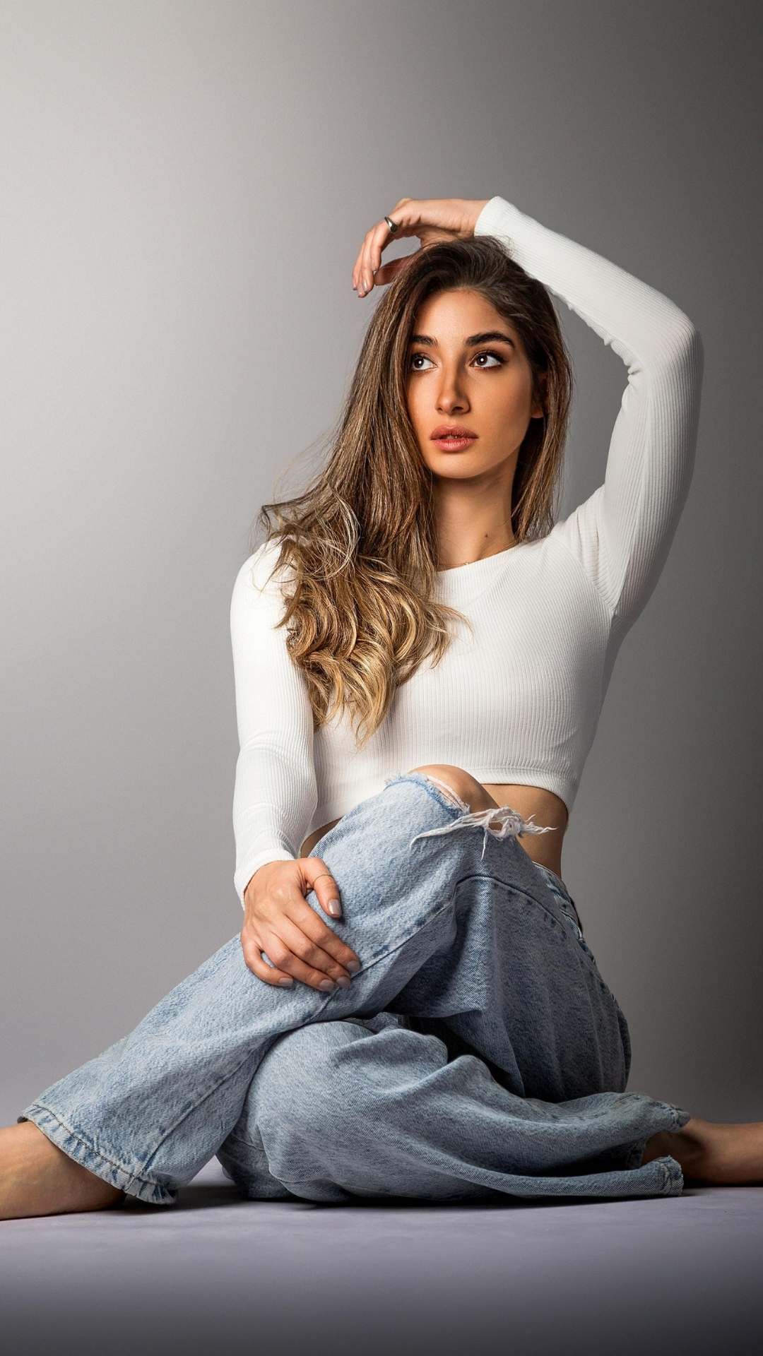 Lady-stylishly-sitting-on-the-floor-with-legs-crossed-wearing-a-white-fitted-top-and-jeans-perfect-for-spring-casual-fashion.