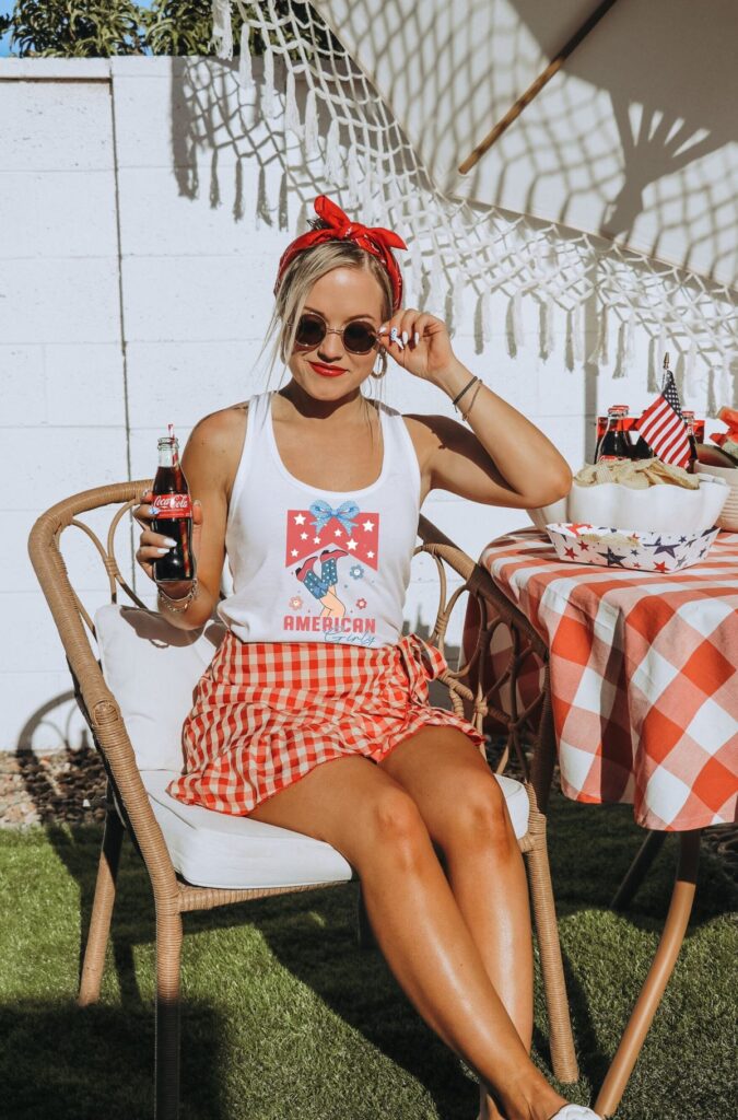Budget-friendly-4th-of-shirt-ideas-showing-a-woman-wearing-singlet-and-skirt-while-sitting-down