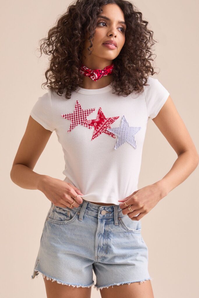 A-woman-wearing-a-white-shirt-has-DIY-star-stencil-on-it-with-short-for-4th-of-july-shirt-ideas
