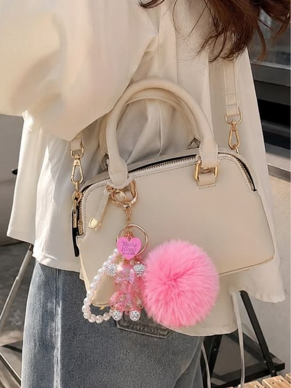 Picture-of-a-woman-carrying-a-handbag-that-has-a-pom-pom-charm-attached-to-it