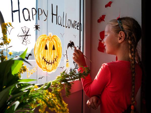 Featured-image-of-11-easy-Halloween-crafts-for-preschoolers-to-make-at-home-showing-picture-of-small-kid-designing-the-window-with-Halloween