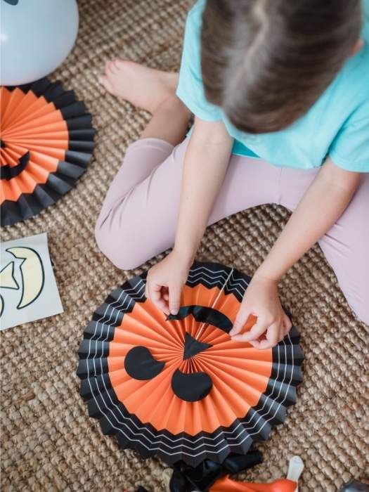 Halloween-paper-crafts-for-kids-showing-a-kid-with-an-orange-and-black-paper-face