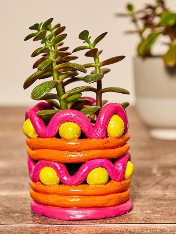 An-image-of-a-painted-coil-clay-pot-and-a-flower-inside-it-as-flower-vase