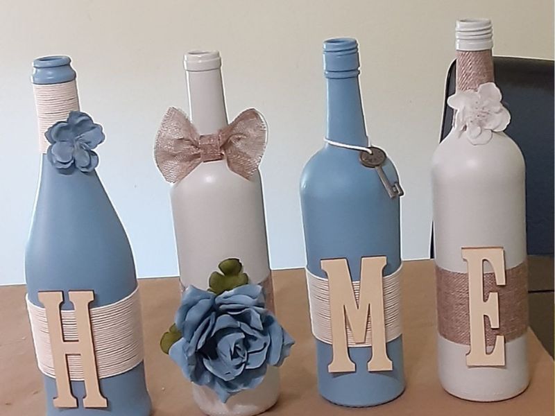 Featured-image-of-wine-bottle-crafts-showing-a-beautiful-4-bottles-painted-with-blue-and-white-and-decorated-with-home-alphabets-designs